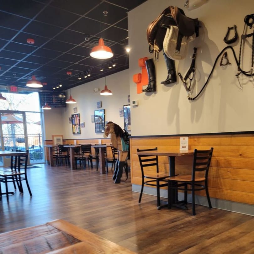 Interior of Mane Course Sandwiches with equestrian decor, wooden horse, tables, and chairs.