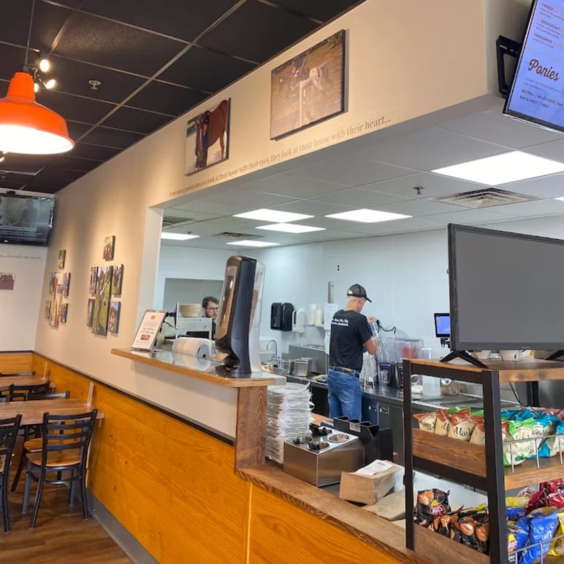 Interior of Mane Course Sandwiches with counter, menu, and horse-themed decor.